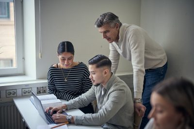 Lärare hjälper två elever med en uppgift