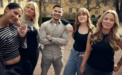 Fem glada elever står tillsammans utomhus