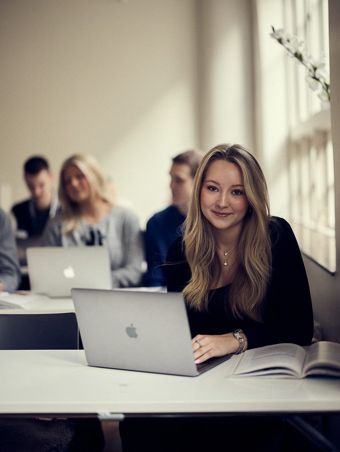 Elev framför en dator kollar in i kameran