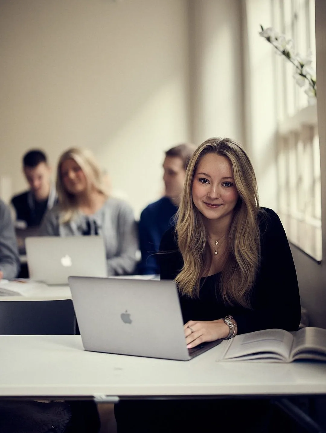 Elev framför en dator kollar in i kameran