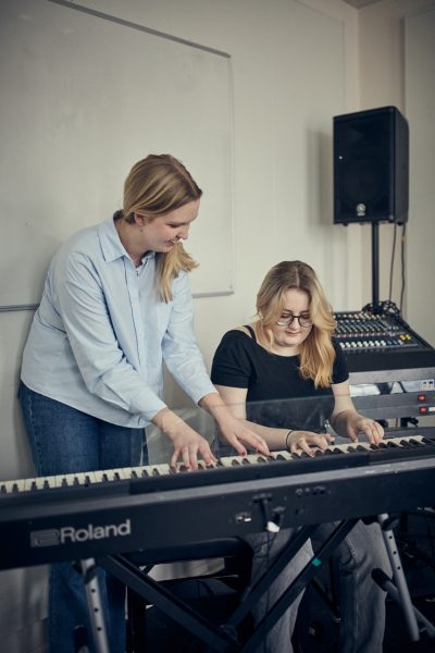 Elev och lärare spelar piano