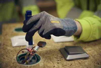 Närbild på en hand som mäter spänning i ett eluttag