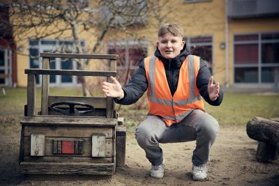 Elev i reflexväst ute i en lekpark