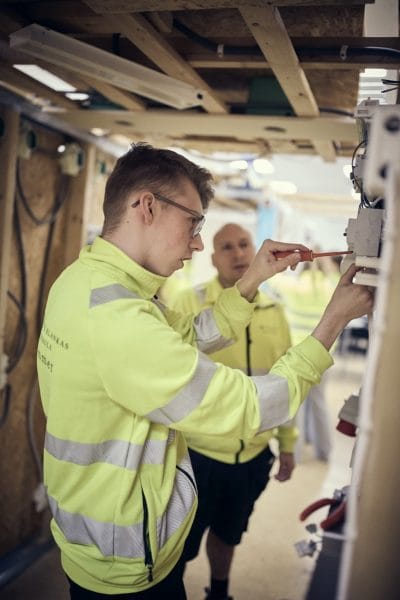 Elev i arbetskläder installerar ett eluttag