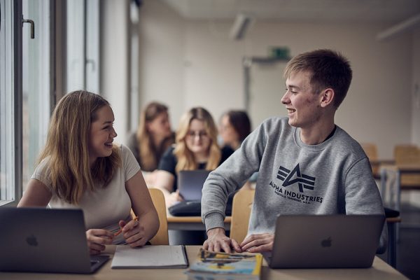 Två elever tittar nöjt på varandra i ett klassrum