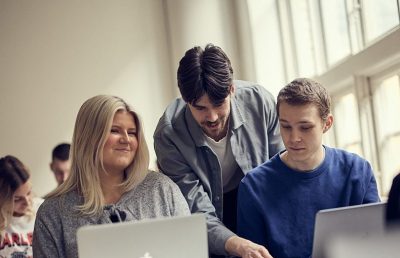 Lärare förklarar en uppgift för två personer
