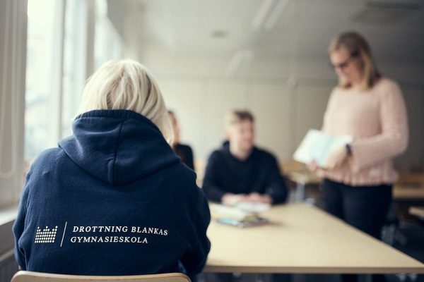 Visar ryggen av en elev som har en mörkblå hoodie med DBGYs logga