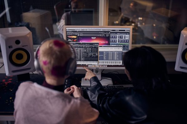 Två elever mixar musik och pekar på en skärm