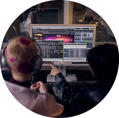 Två elever producerar musik och pekar på ett digitalt mixerbord