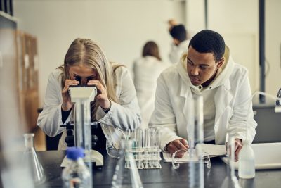 Elever i vita rockar i en labbsal