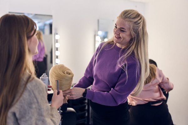 Elev sätter upp håret på en docka