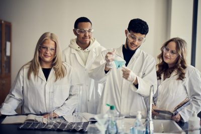 Elever i labbrockar genomför en laboration