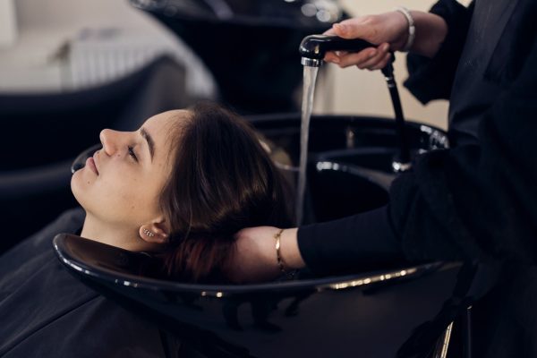 Tjej får sitt hår tvättat ev en elev