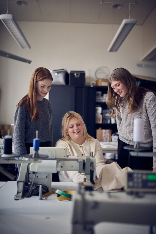 Tre elever framför en symaskin