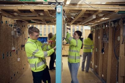Elever i arbetskläder skruvar installerar eluttag