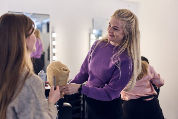 Elev sätter upp en frisyr på en docka
