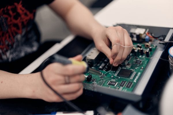 Närbild på händer som löder på ett kretskort