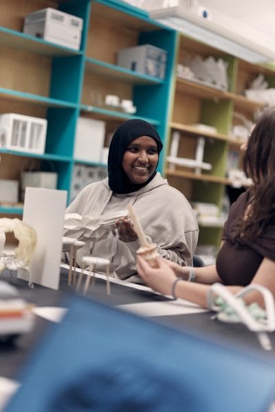 Elev sitter i klassrum och visar upp sin design