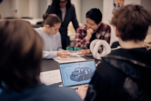 Laptop med bid av en bildesign med elever i bakgrunden