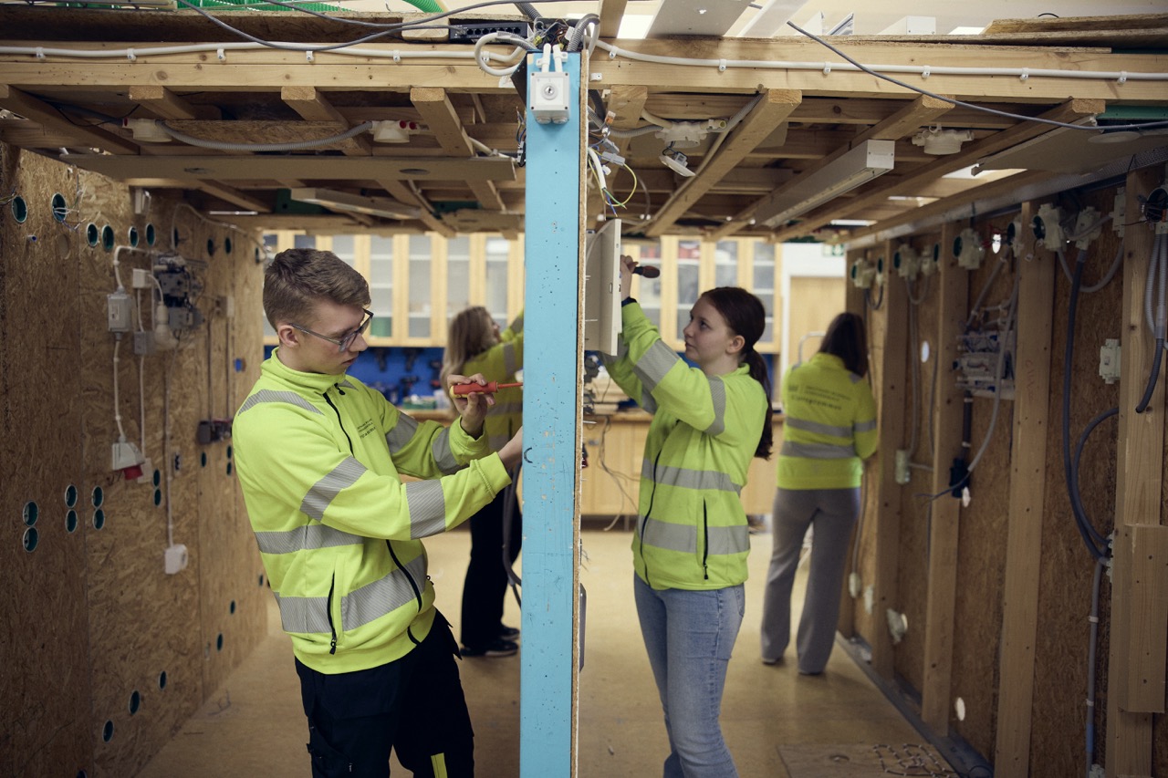 Elever i arbetskläder skruvar installerar eluttag