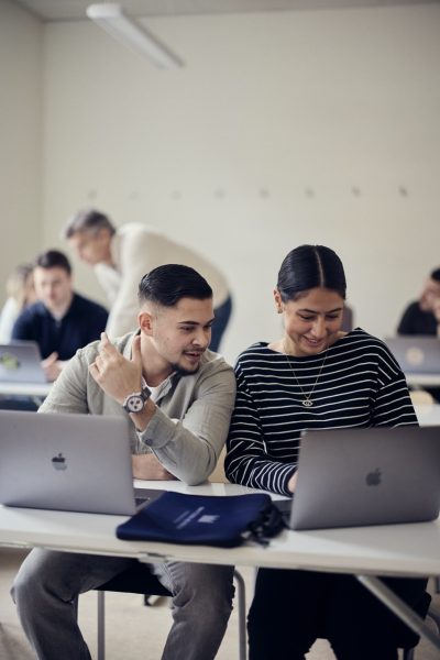 Två elever pluggar med sina datorer