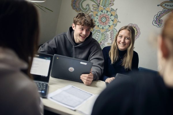 Två elever med sina datorer i ett klassrum